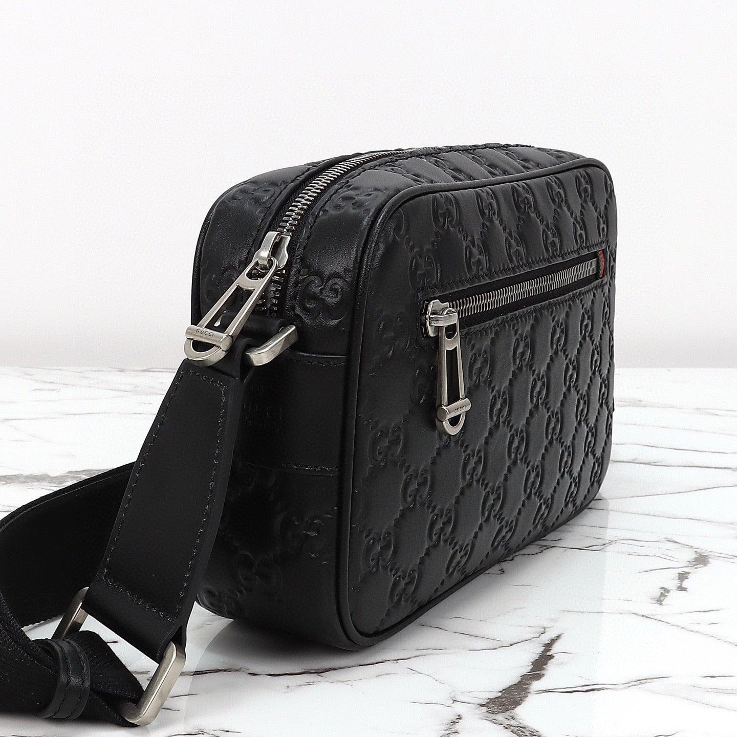 Gucci Sac Bandoulière Gucci GG Embossed Disponible en Beige ou Noir avec Zip Frontal Web Stripe